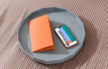 iPhone 17 Pro mockup on a gray tray with an orange notebook