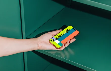 iPhone 17 Pro mockup held in a hand against a green shelf